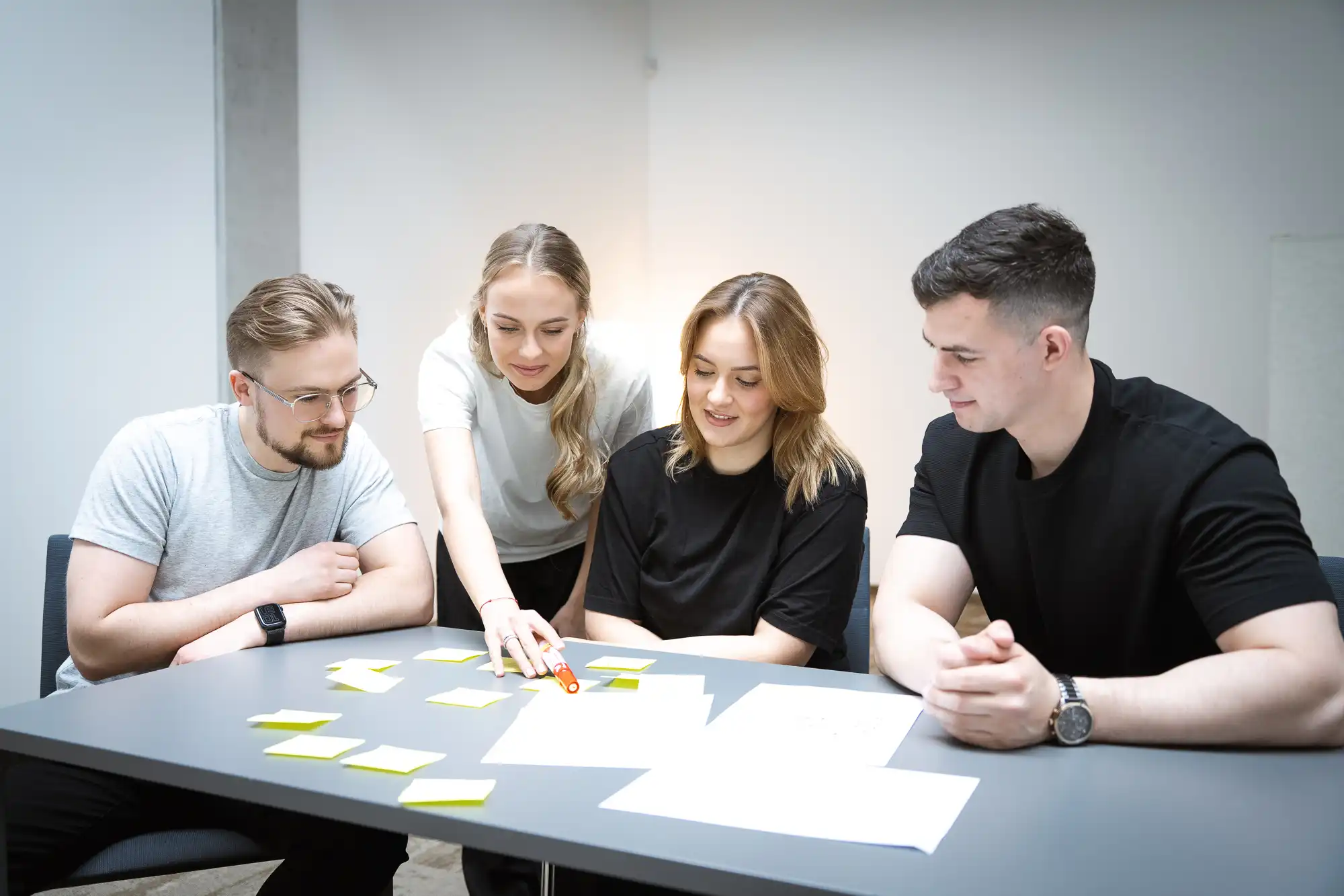 Group of students collaborating around a table using yellow sticky notes for brainstorming.