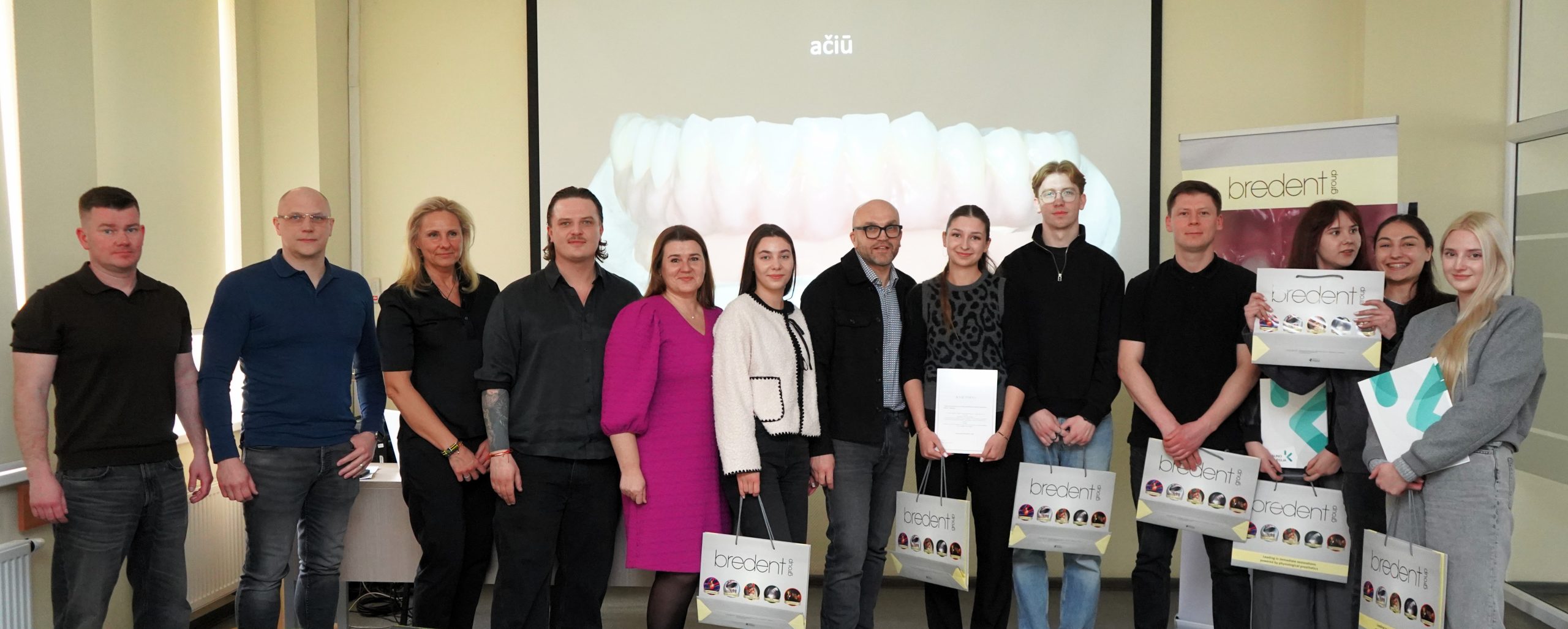Po dantų technologų profesinio meistriškumo konkurso bendroje nuotraukoje įsiamžino studentai, vertinimo komisijos nariai ir socialiniai partneriai su apdovanojimais bei rėmėjų dovanomis.