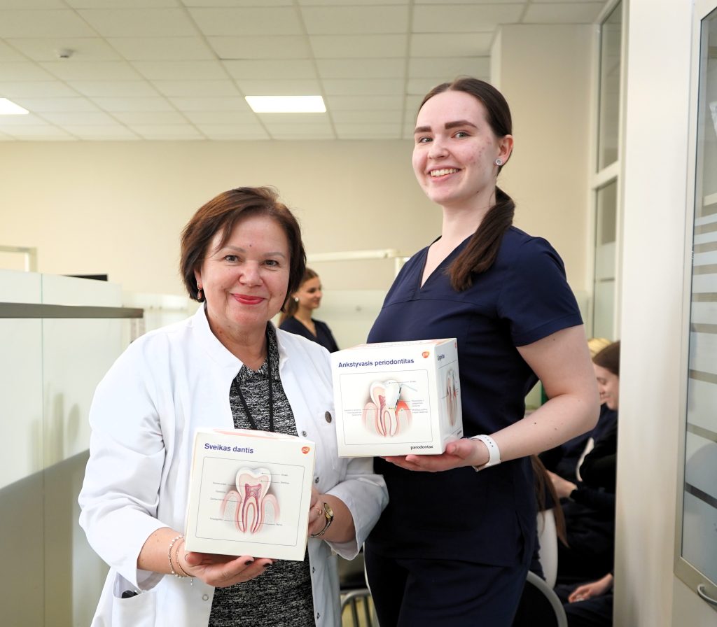 Burnos sveikatos edukacija Kauno kolegijos Medicinos fakultete – dėstytoja ir studentė demonstruoja danties sandaros modelius, naudojamus mokant apie ėduonies prevenciją ir burnos priežiūrą.