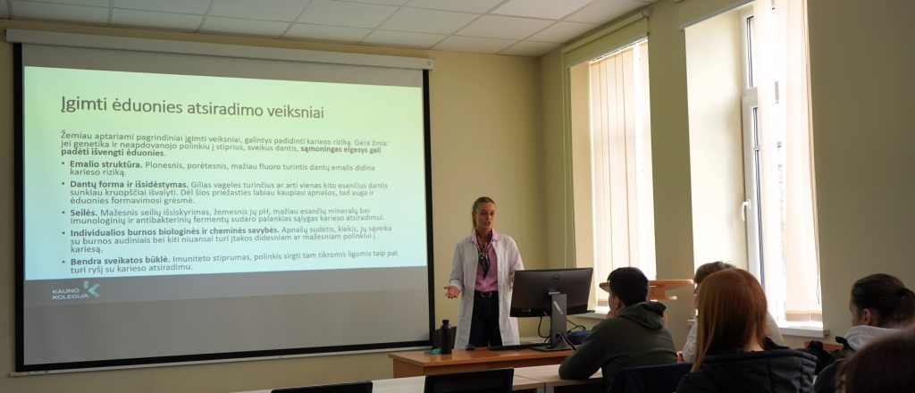 Burnos sveikatos edukacija Kauno kolegijos Medicinos fakultete – dėstytoja pristato ėduonies atsiradimo veiksnius, o gimnazistai klausosi paskaitos auditorijoje.