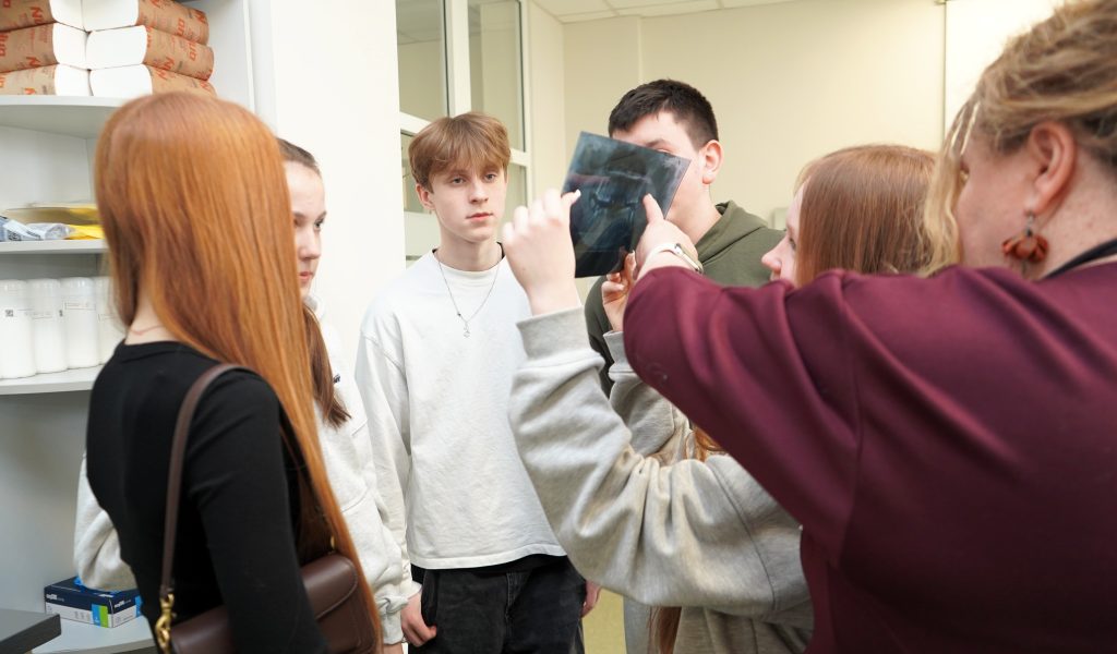 Gimnazistai apžiūri dantų rentgeno nuotrauką ir susipažįsta su burnos sveikatos tyrimo metodais.