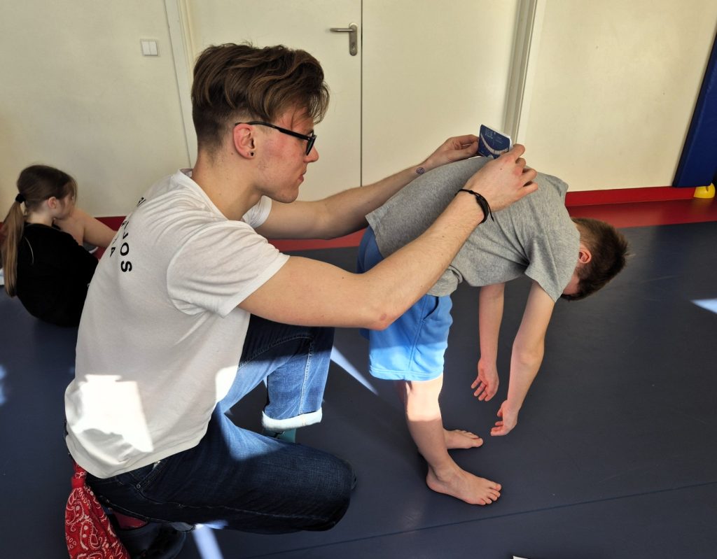 Praktinio užsiėmimo metu Kauno kolegijos Medicinos fakulteto kineziterapijos studentas stebi vaiko laikyseną pasilenkimo pozicijoje.