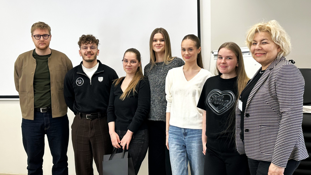 Trečio kurso Kosmetologijos studijų programos studentai, „CLM Beauty Lab“ atstovai ir katedros vedėja po verslo iššūkių pristatymų stovi auditorijoje ir pozuoja bendrai nuotraukai.