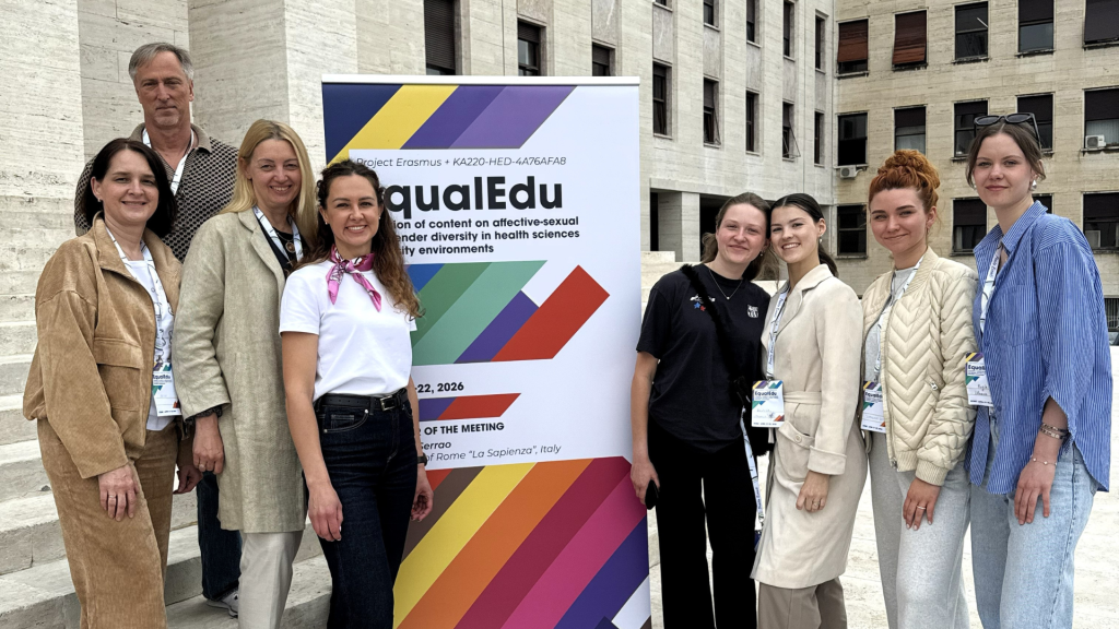EqualEdu partnerių susitikimas Romos Sapienza universitete: Kauno kolegijos Medicinos fakulteto atstovai stovi prie projekto stendo universiteto kieme.