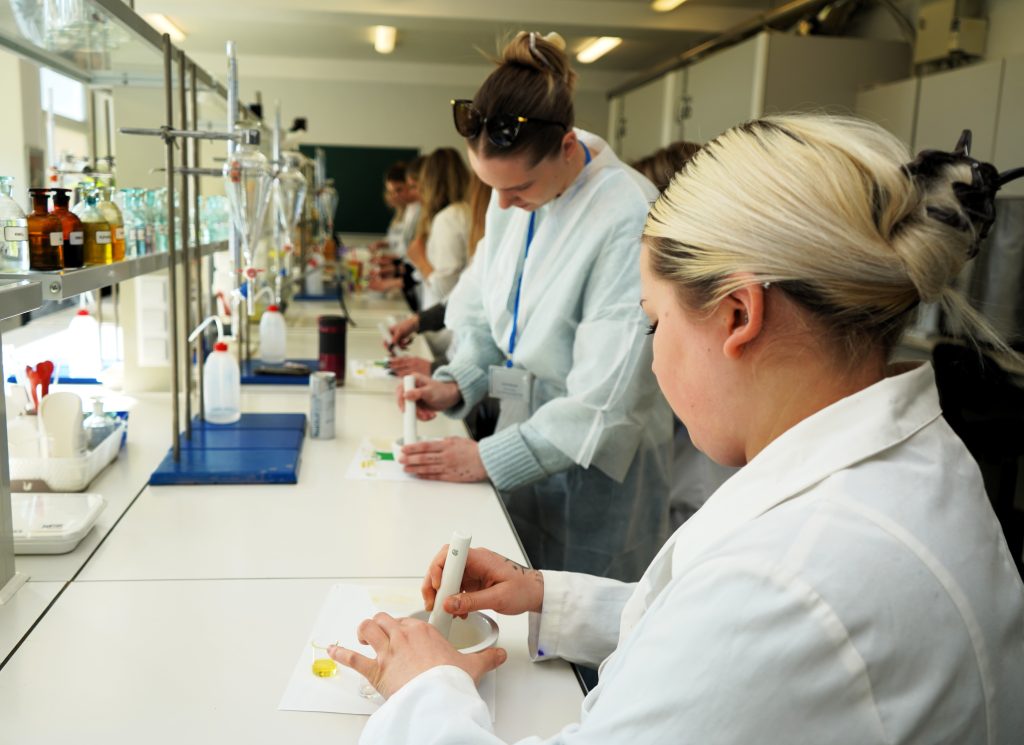 Laboratorijoje BIP dalyvės praktinių dirbtuvių metu ruošia priemones ir dirba su indais bei medžiagomis.