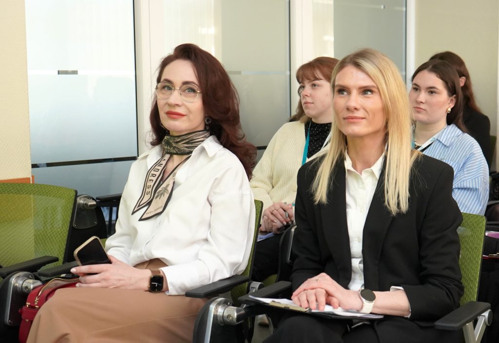 Konferencijos „Mokslas ir studijos: 2026“ dalyvės sėdi auditorijoje ir klausosi pranešimų, laikydamos užrašus.
