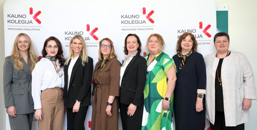 Medicinos fakulteto bendruomenės narės ir socialiniai partneriai pozicionuoja bendrai nuotraukai konferencijoje „Mokslas ir studijos: 2026“ prie Kauno kolegijos stendo.