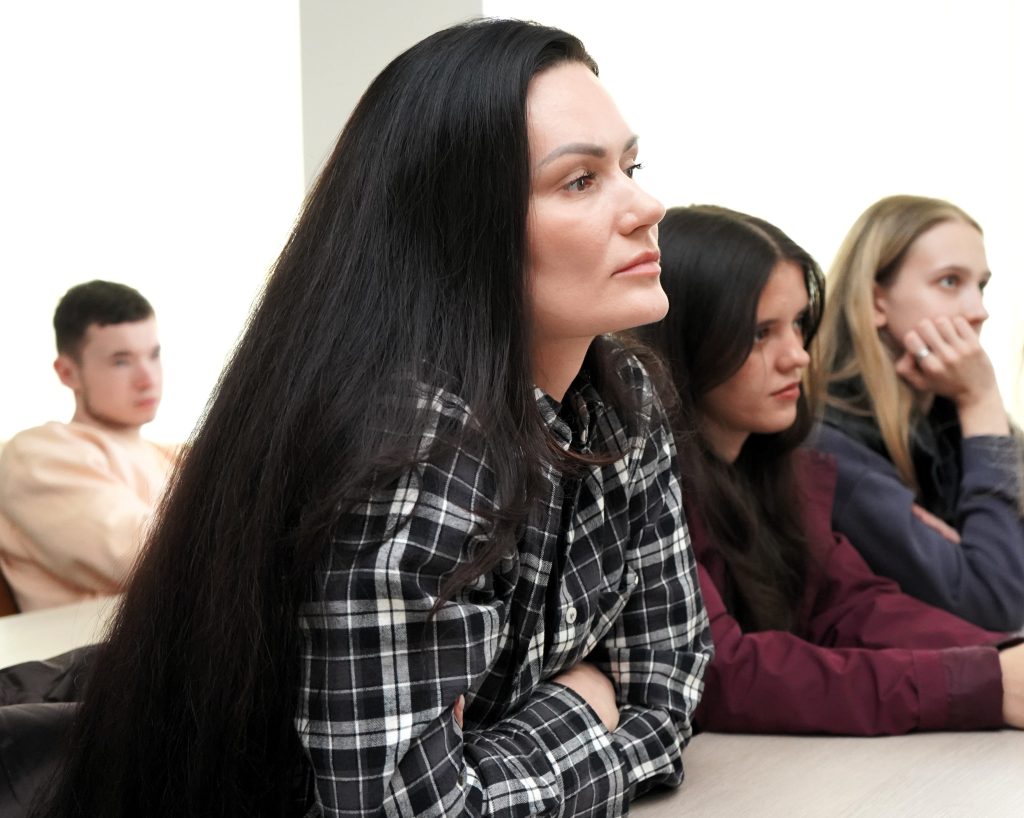 Studentai auditorijoje susikaupę klausosi pranešimo konferencijoje