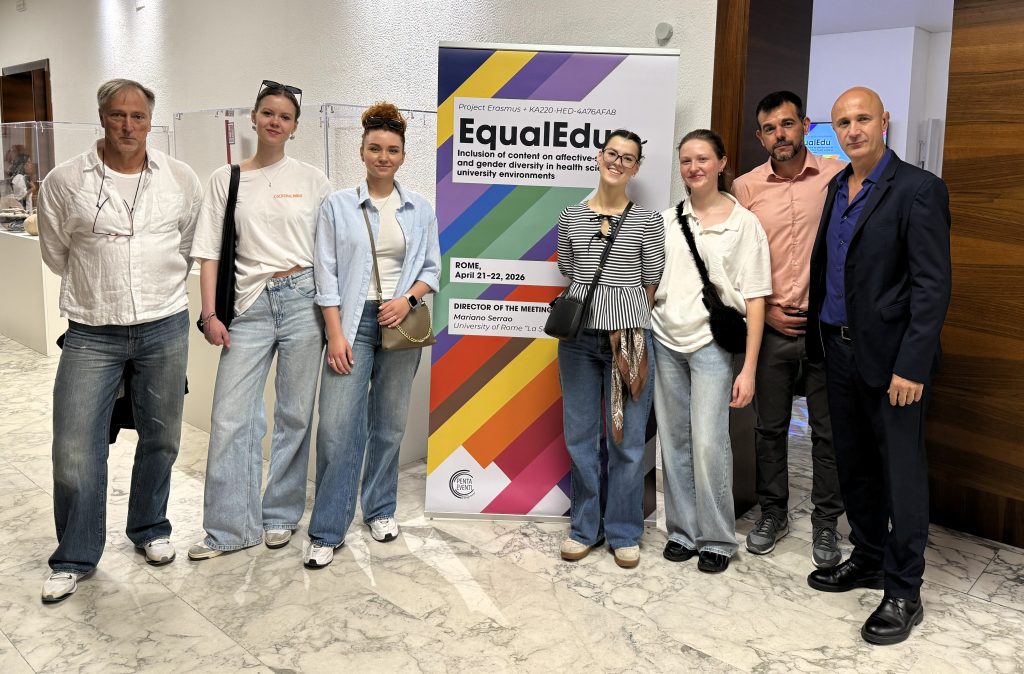 EqualEdu partnerių susitikimas Romoje: projekto dalyviai stovi prie EqualEdu stendo universiteto patalpose.