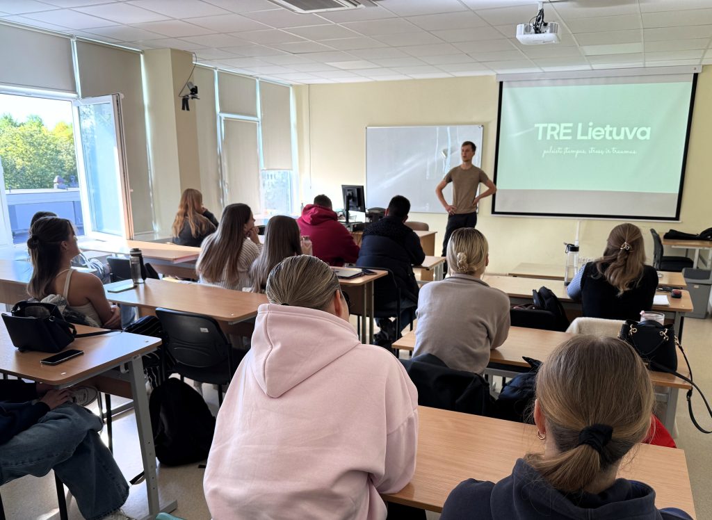 Kineziterapijos alumnas skaito pranešimą studentams auditorijoje apie darbą ir profesinę patirtį