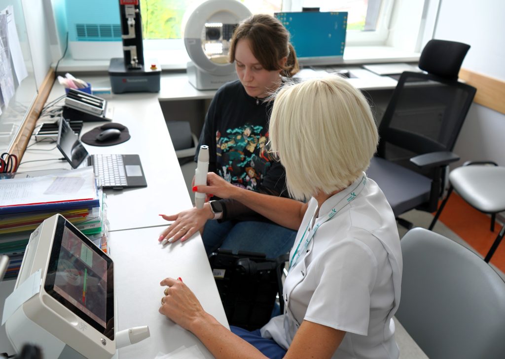 Studentei atliekamas odos parametrų vertinimas naudojant pažangią diagnostikos įrangą.