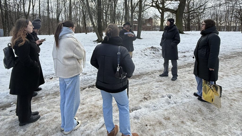 Žiemiškame parke ant apsnigto tako stovi ir gido klauso studentų grupė.