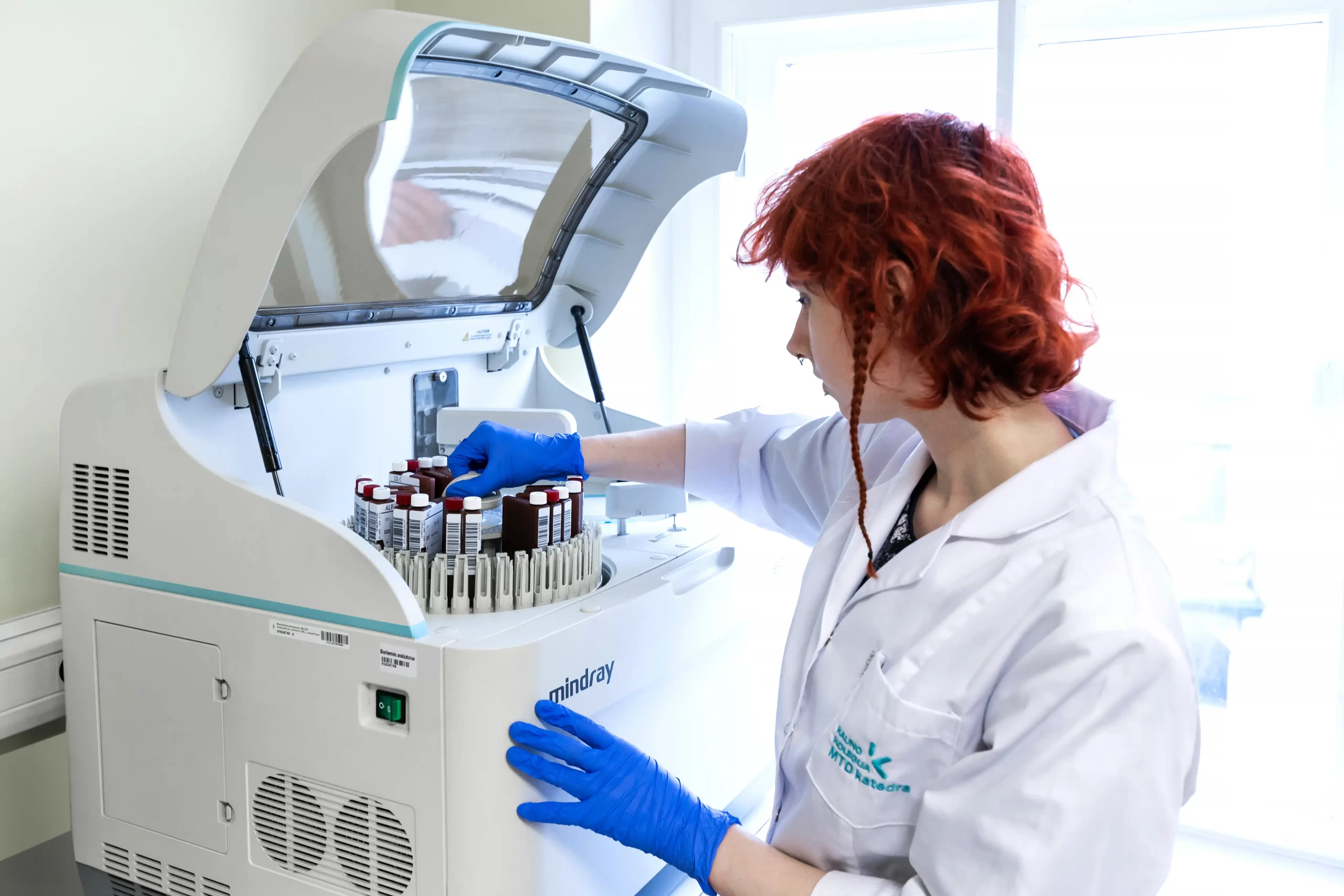 Kauno kolegijos studentė laboratorijoje deda mėginius į Mindray analizatorių.