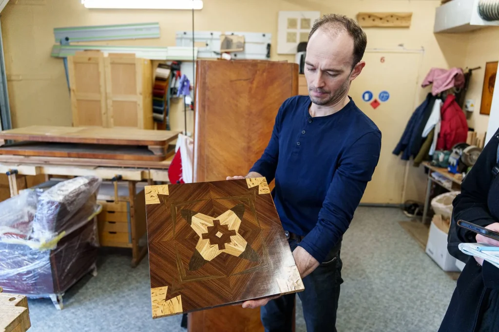 Dėstytojas A. Blažinauskis rodo tarpukario raštus, sukurtus marketri technika / R. Tenio nuotr.