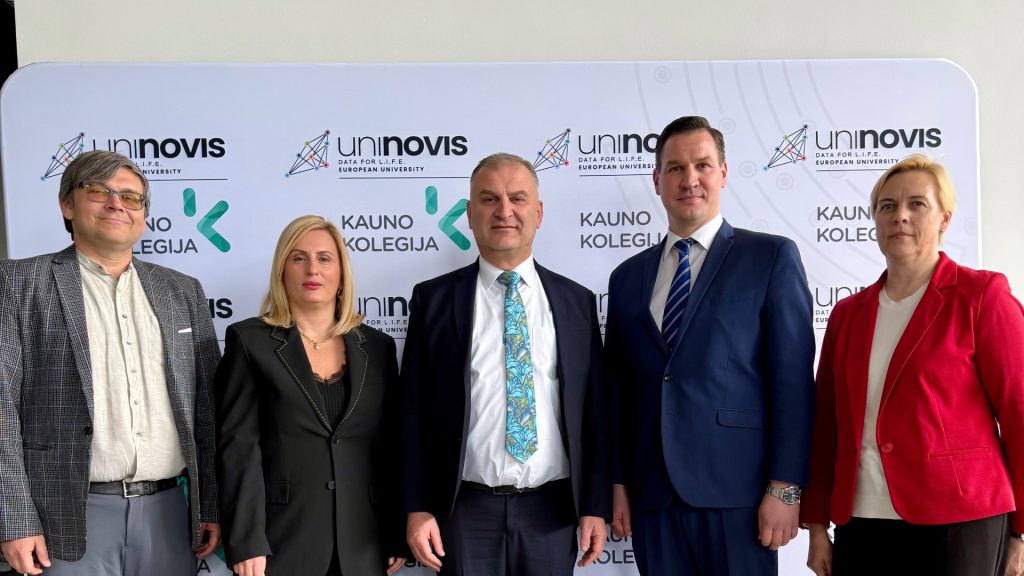 Kauno kolegijos ir Kaukazo universiteto (Sakartvelas) vadovų susitikimo dalyviai stovi priešais sienelę su Kauno kolegijos ir UNINOVIS aljanso logotipais.