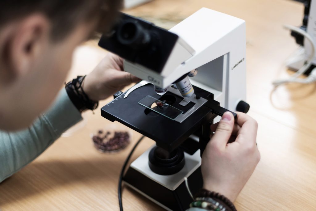 Studentas laboratorijoje mikroskopu tiria augalinės kilmės mėginį per Agroverslų technologijų studijų praktinį užsiėmimą Kauno kolegijoje